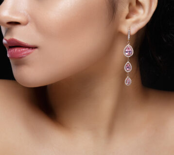 Long earring with violet precious stones hang from woman's ear