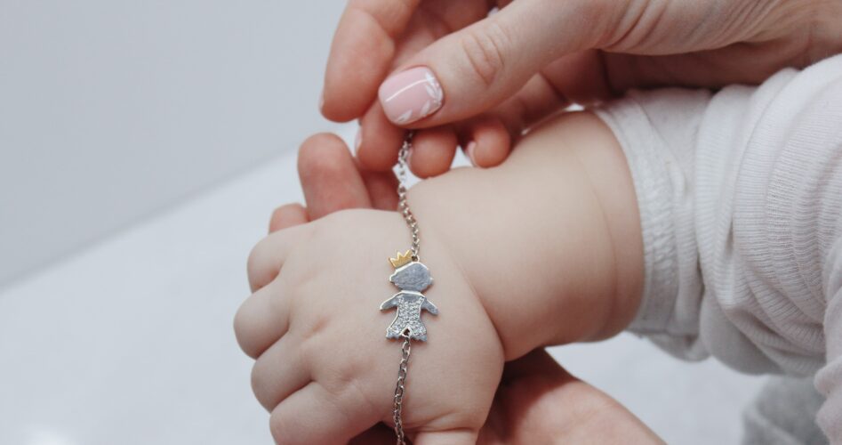 closeup-shot-female-putting-cute-bracelet-her-baby-s-hand